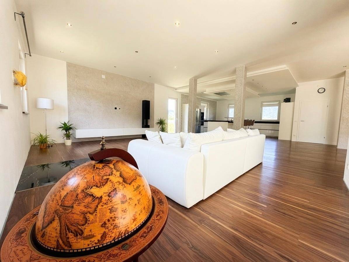 Heller Wohnbereich mit Holzboden, weißer Couch und dekorativem Globus, der den Raum schmückt.
