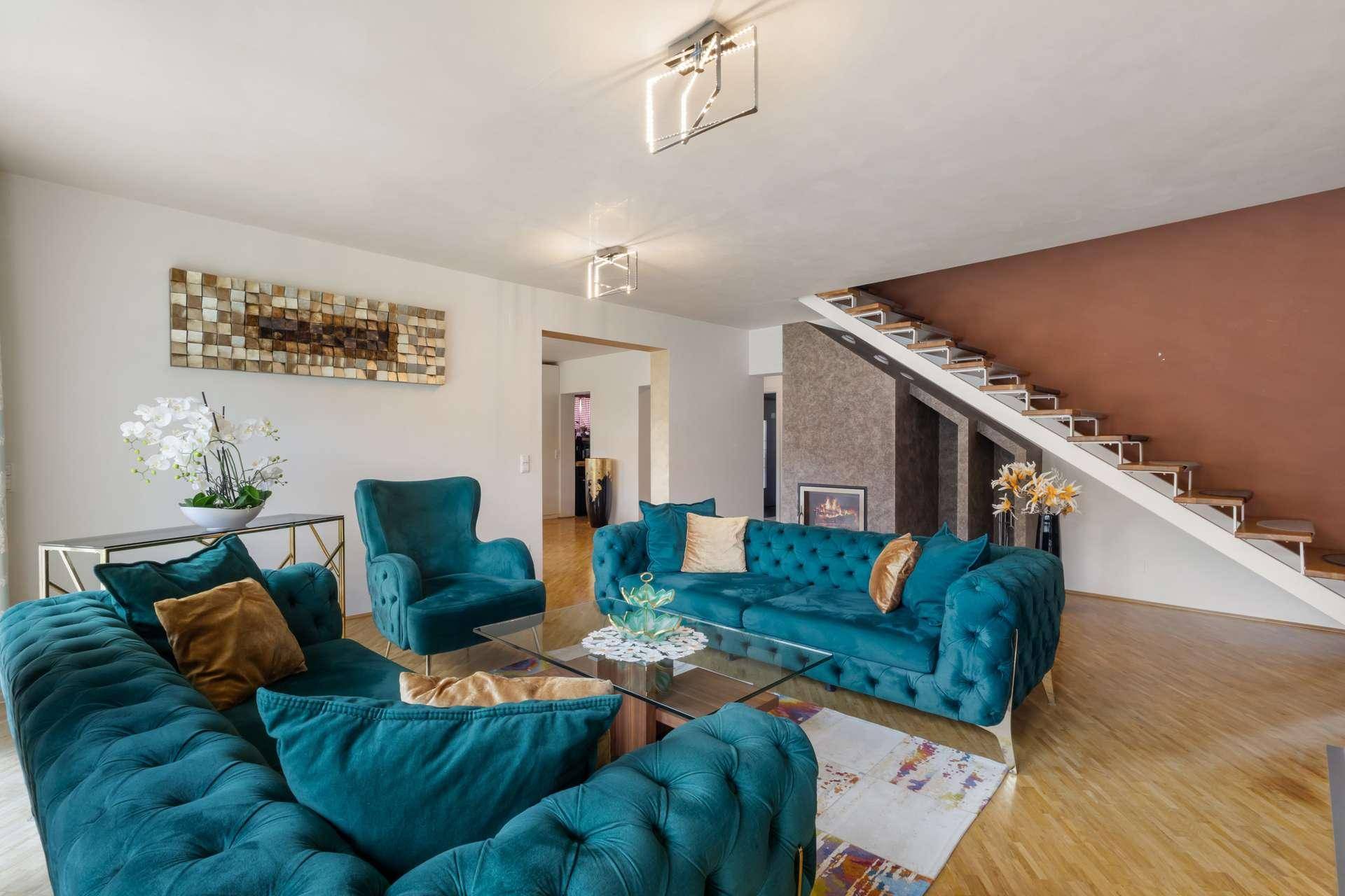 Geräumiges Wohnzimmer mit stilvollen Sofas, Kamin und offener Treppe zum Obergeschoss.