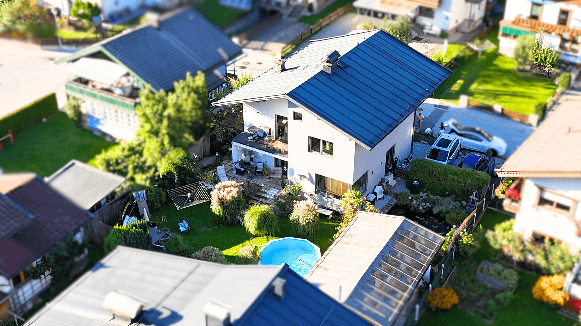 Luftaufnahme eines Einfamilienhauses mit gepflegtem Garten und kleinem Aufstellpool.