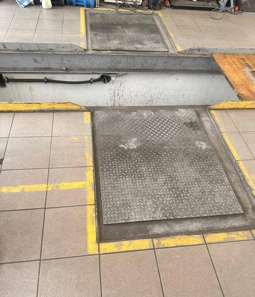 Abgedeckte Inspektionsgrube mit robusten Riffelblechplatten im Boden einer professionellen Werkstatt.