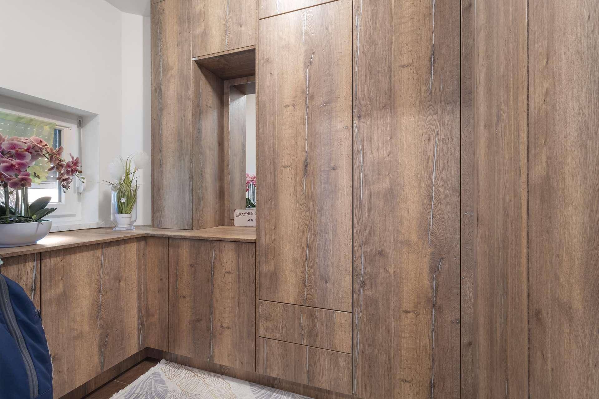 Maßgefertigte Holzschränke im Eingangsbereich mit integriertem Spiegel und Fenster.