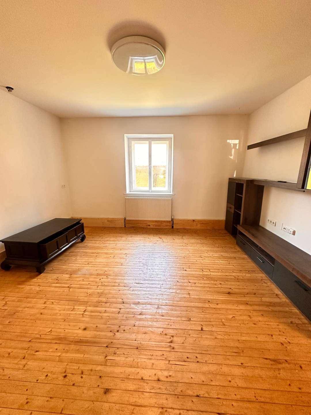 Heller Raum mit Holzdielenboden, weißen Wänden und einem Fenster, bereit zur Einrichtung.