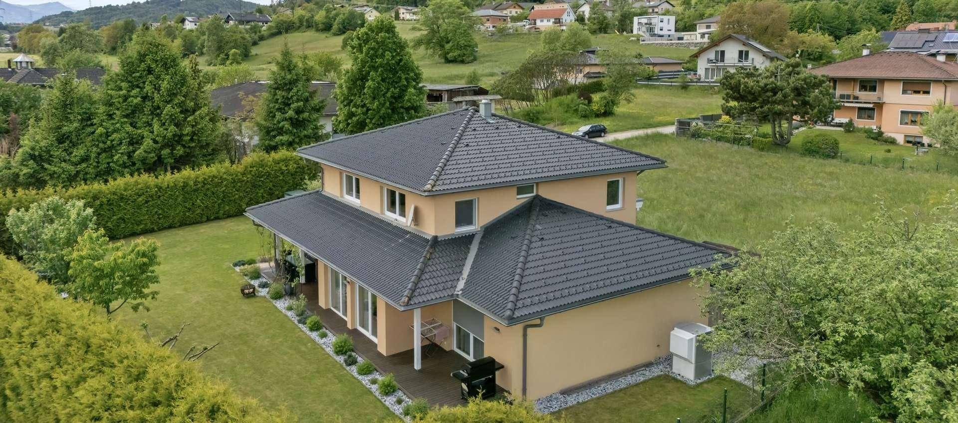 Luftaufnahme eines Einfamilienhauses mit großem Garten und umliegender Wohnbebauung.