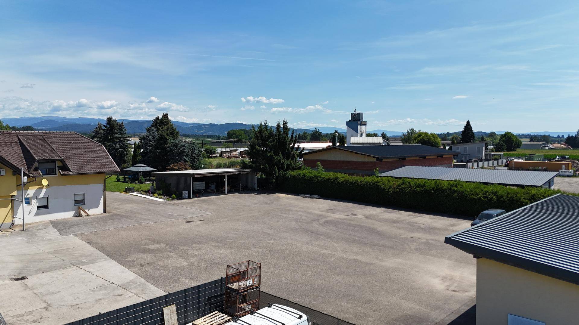 Luftaufnahme eines Wohnhauses mit großem Vorplatz und Blick auf die weite Landschaft und den Horizont.