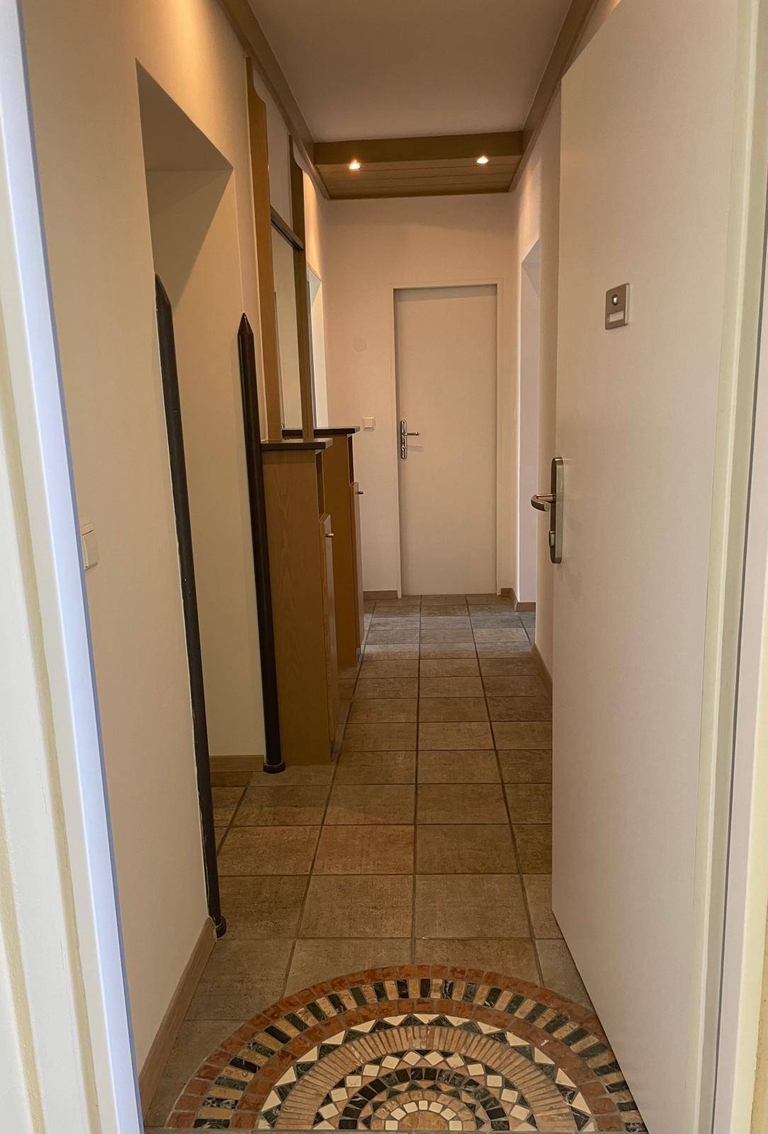 Heller Eingangsbereich mit gefliestem Boden und dekorativem Mosaik.
