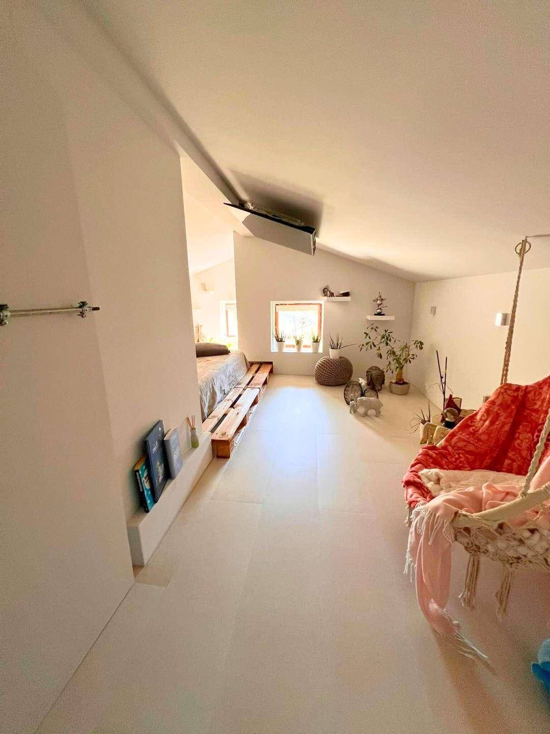 Geräumiger Dachbodenbereich mit Schlafgelegenheit, Schaukel und viel natürlichem Licht.
