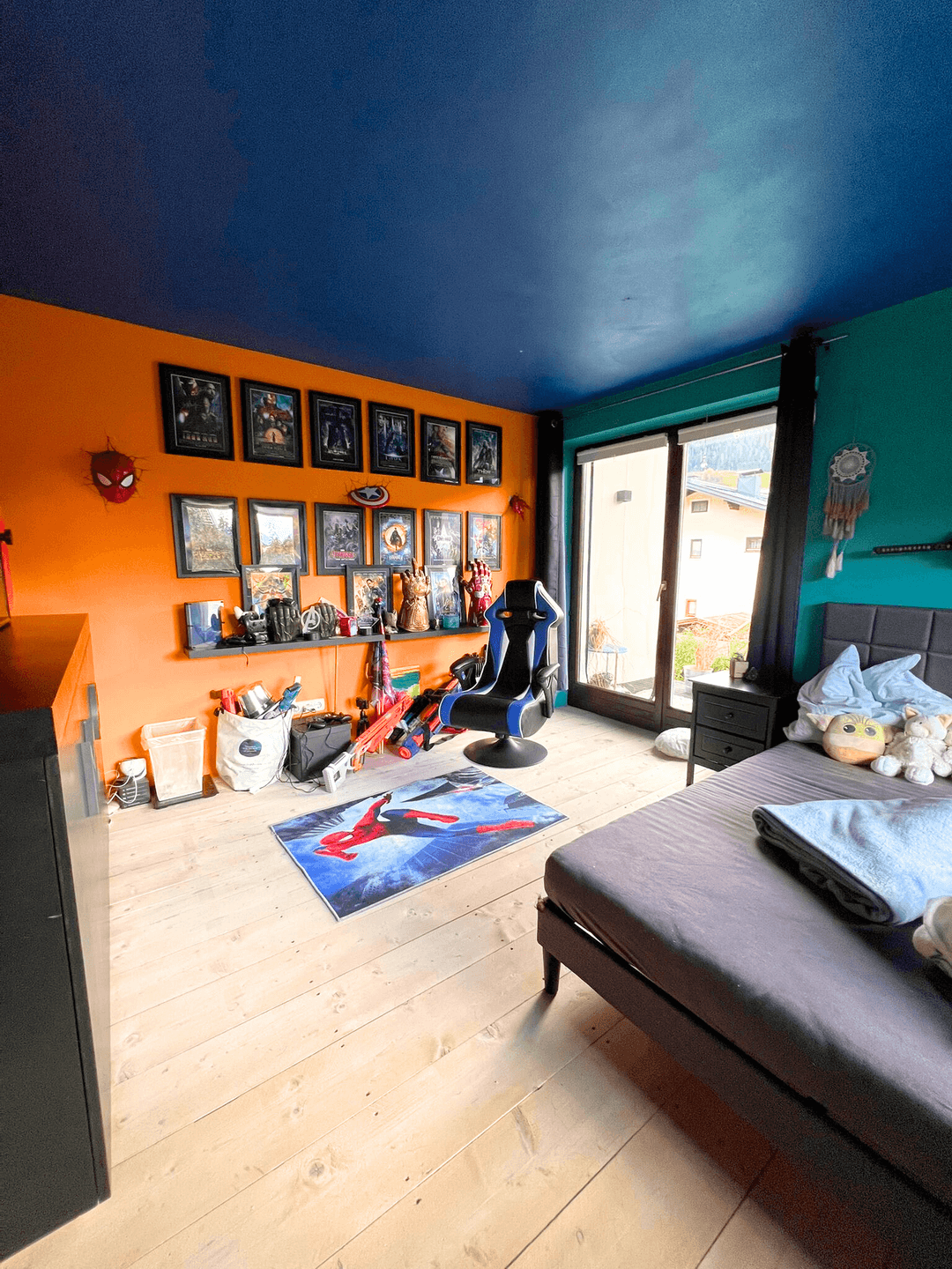 Buntes Kinderzimmer mit Holzboden, Schiebetür zum Balkon und thematischer Dekoration.
