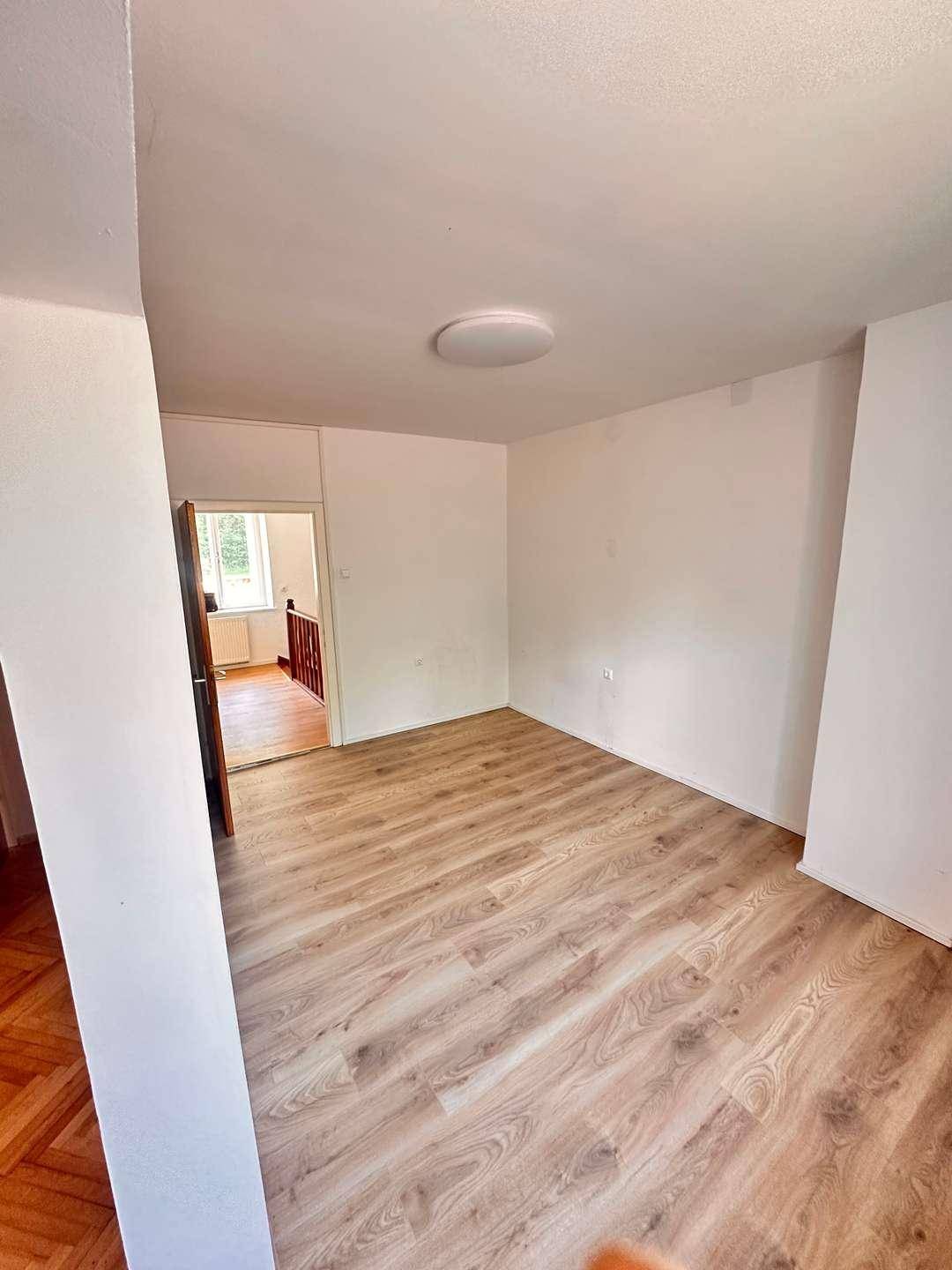Helles Zimmer mit Holzoptik-Laminatboden und weißen Wänden, ideal als Schlaf- oder Arbeitszimmer.