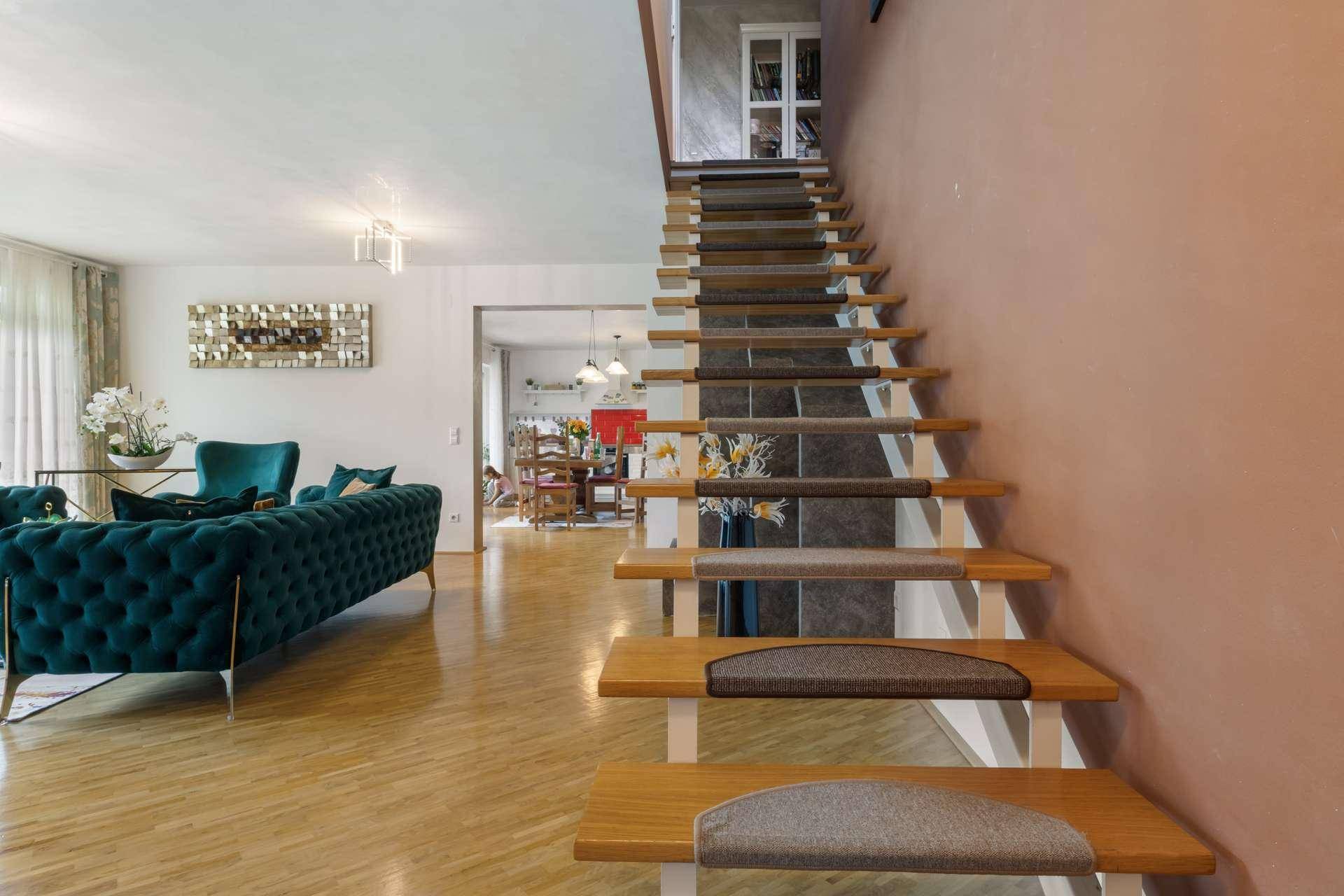 Offene Holztreppe im Wohnzimmer mit Teppichstufen und Blick auf den Essbereich.
