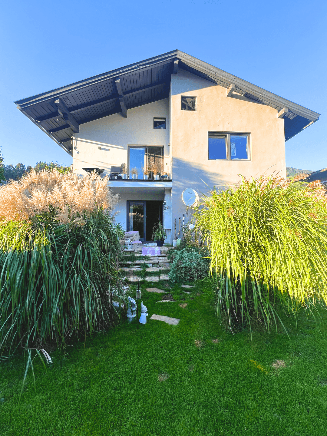 Modernes Einfamilienhaus mit gepflegtem Garten, Terrasse und üppiger Bepflanzung.
