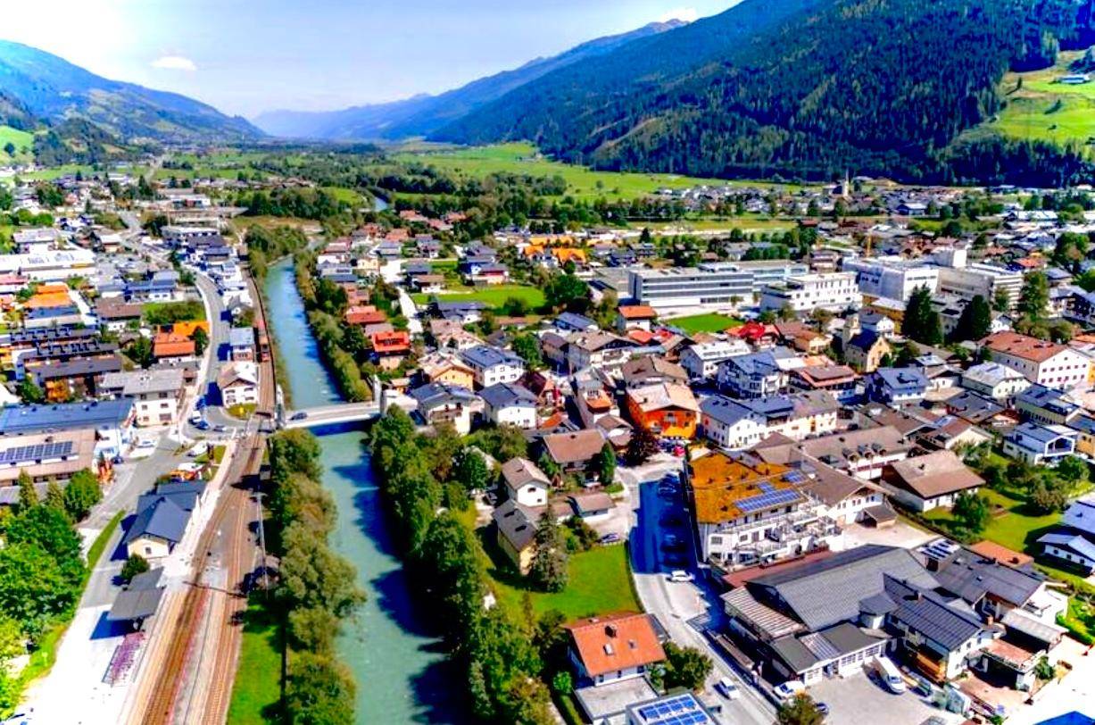Luftaufnahme einer malerischen Stadt im Tal, durchzogen von einem Fluss.