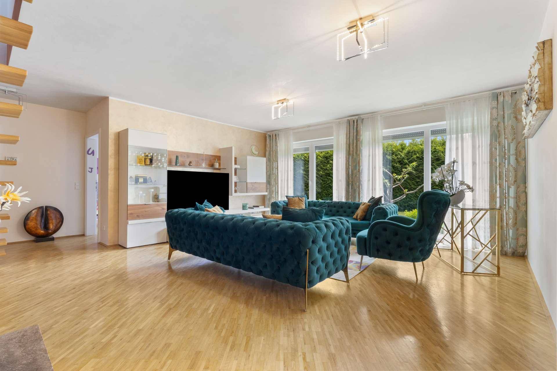 Helles Wohnzimmer mit großen Fenstern, bequemen Sofas und Blick in den Garten.