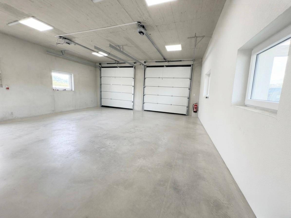 Große Garage mit zwei Rolltoren, Betonboden und viel Platz für Fahrzeuge oder Lagerung.