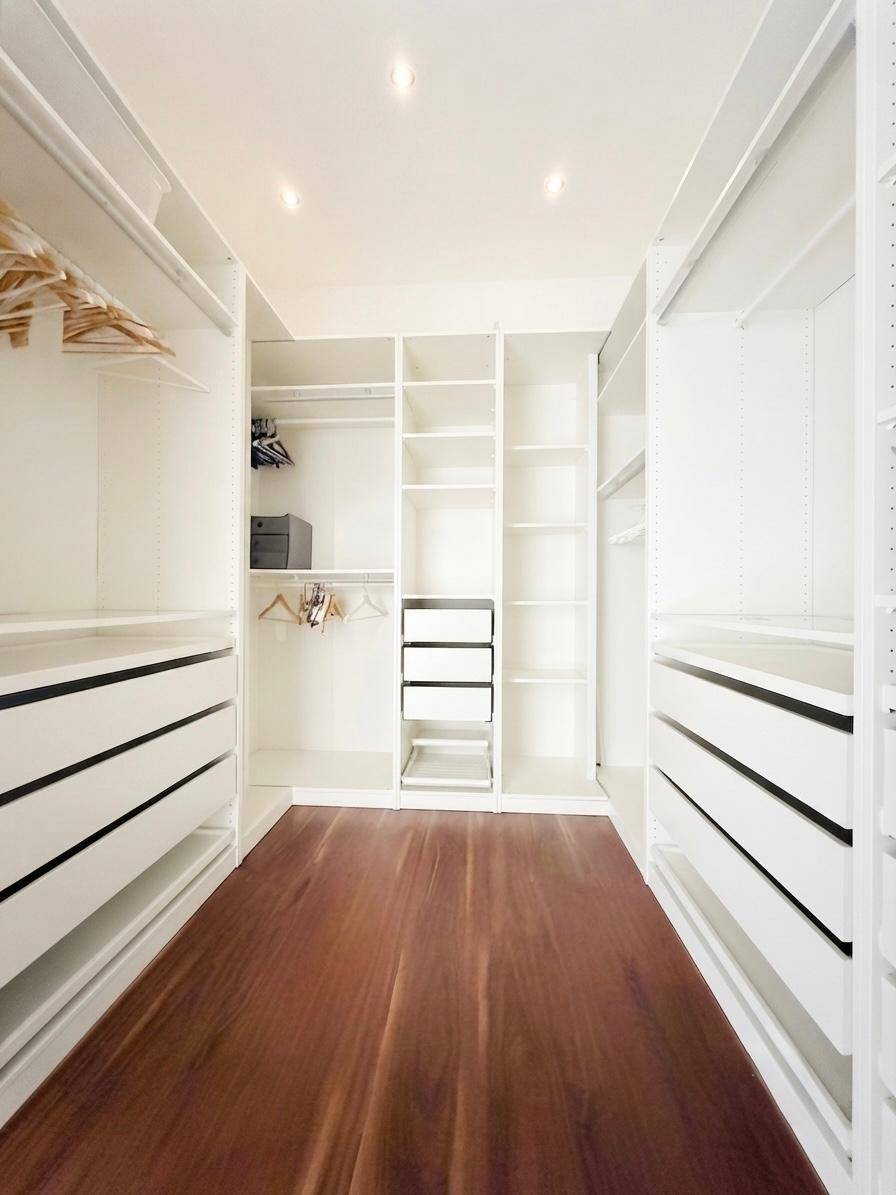 Heller, begehbarer Kleiderschrank mit weißen Regalen und Schubladen, ideal für viel Stauraum.