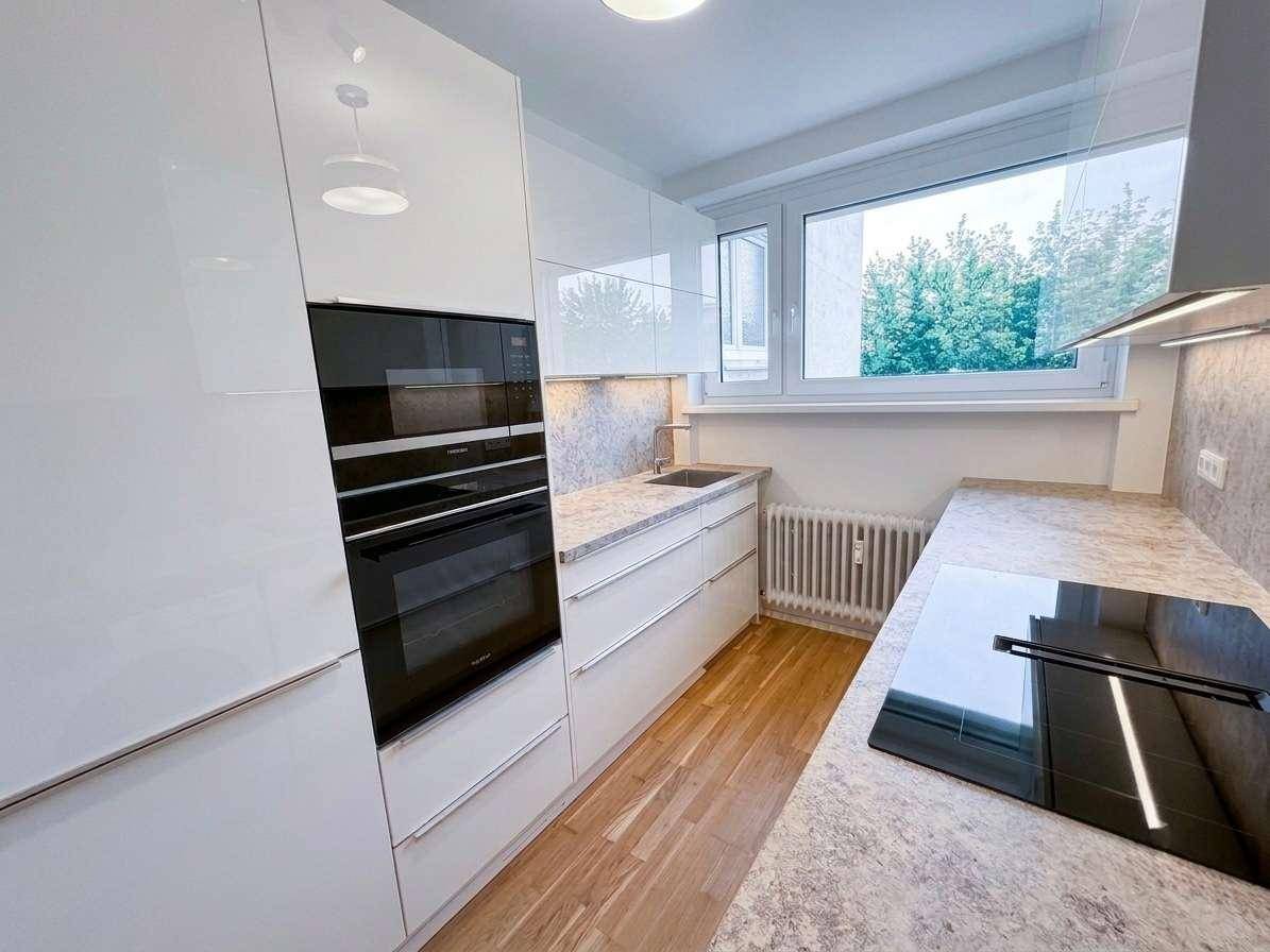 Helle Küche mit weißen Hochglanzfronten, Induktionskochfeld und integriertem Backofen.