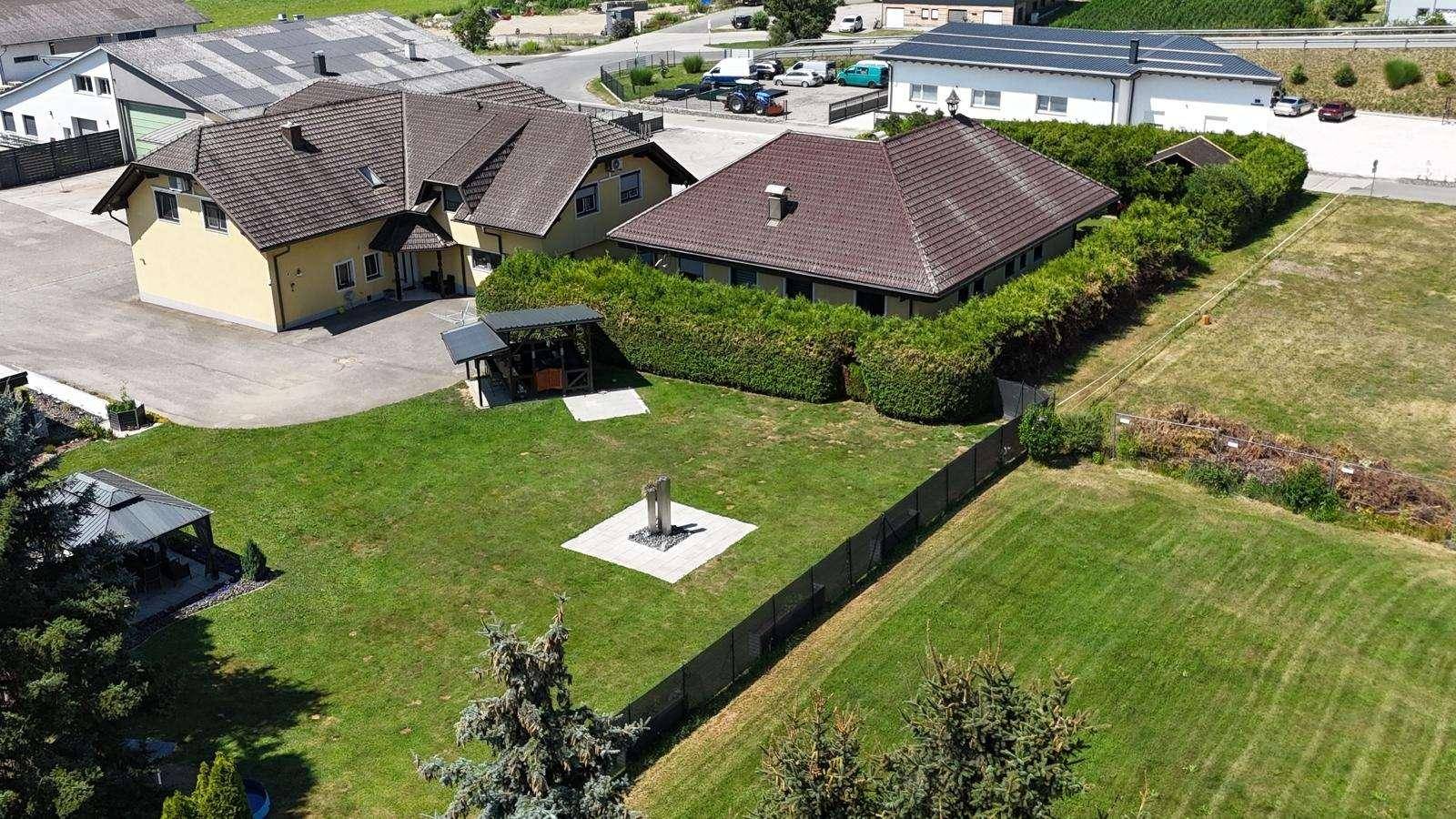 Luftaufnahme des Anwesens mit zwei Gebäuden, großem Garten und umliegender Bebauung.