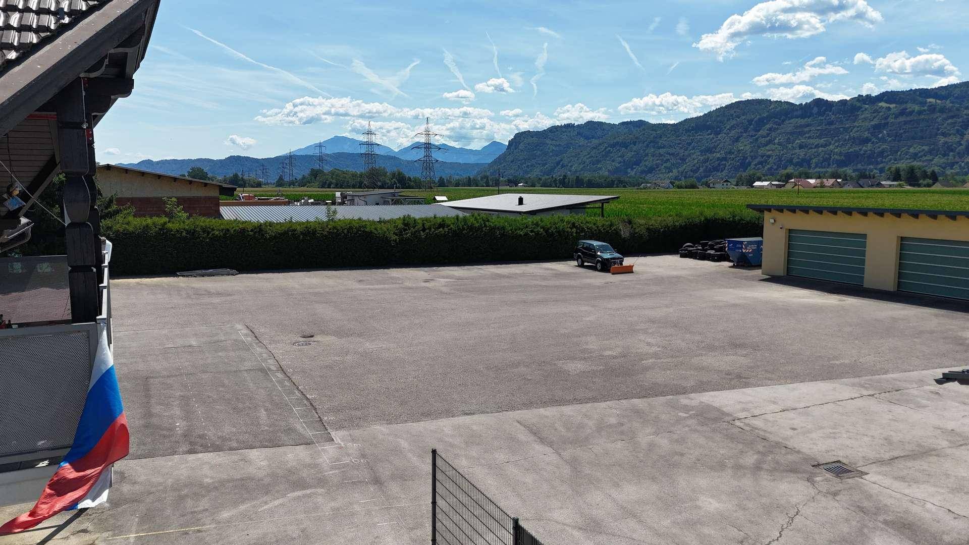 Weitläufiger asphaltierter Bereich vor einem Gebäude mit Blick auf die beeindruckende Berglandschaft.