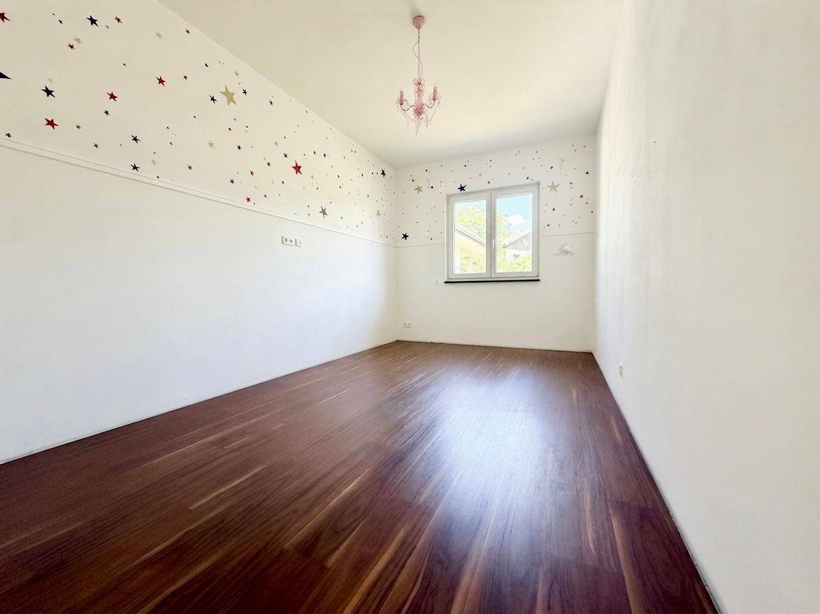 Freundliches Zimmer mit Holzboden und verspielter Sternen-Tapete, ideal für ein Kinderzimmer.