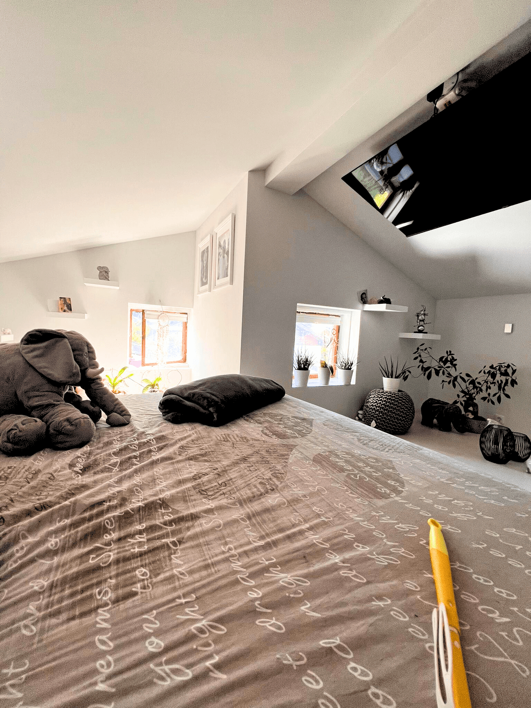 Helles Schlafzimmer im Dachgeschoss mit Palettenbett und mehreren Fenstern.