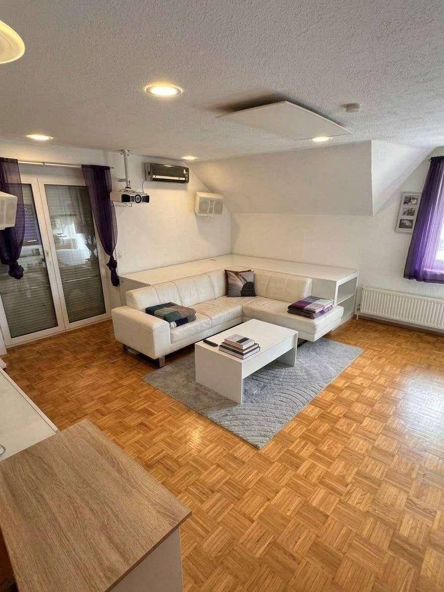 Gemütliches Wohnzimmer mit Parkettboden, weißem Ecksofa und Beamer für Unterhaltung.