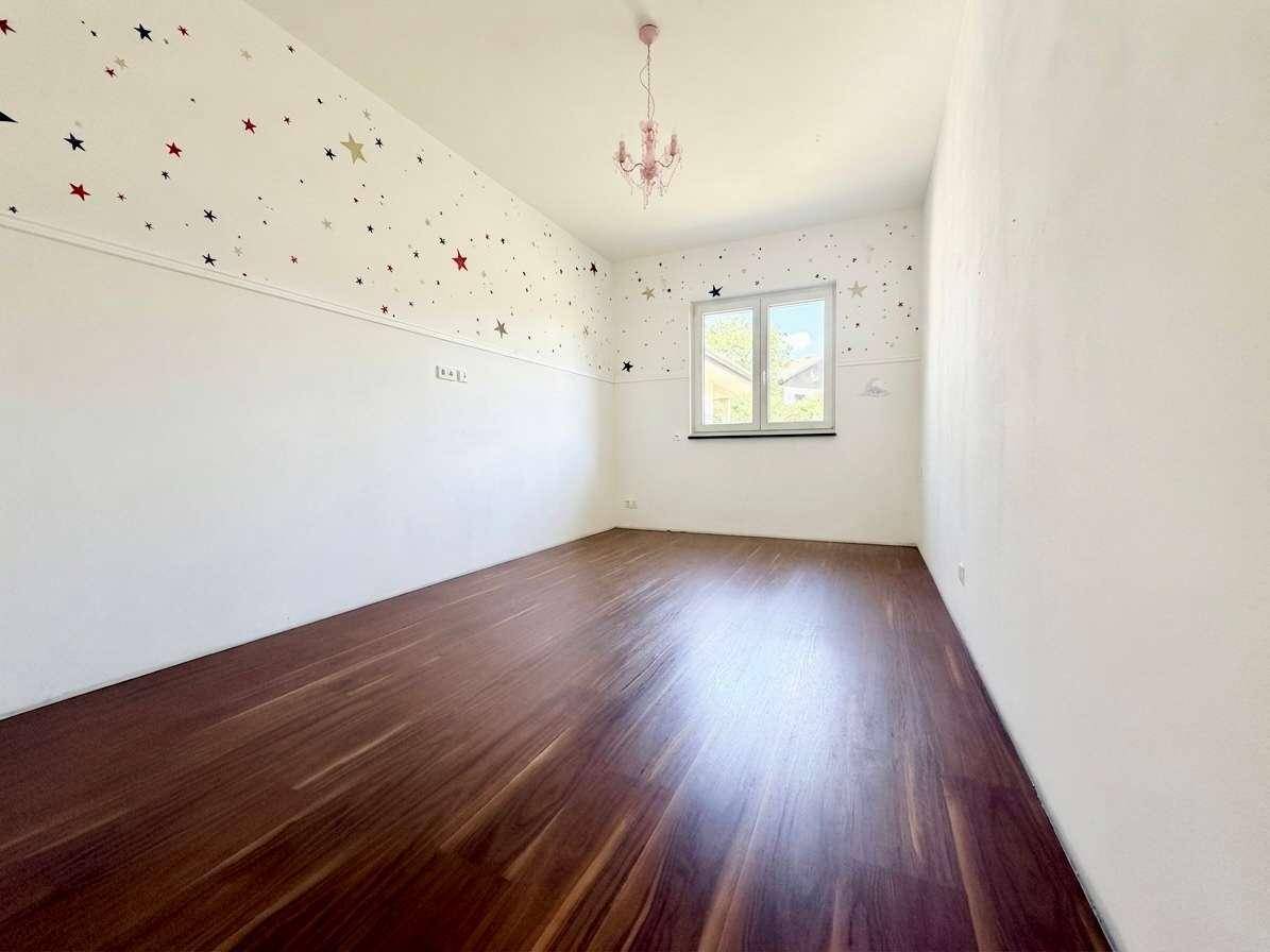 Kinderzimmer mit Holzboden, Sternenmuster an der Wand und einem Fenster.