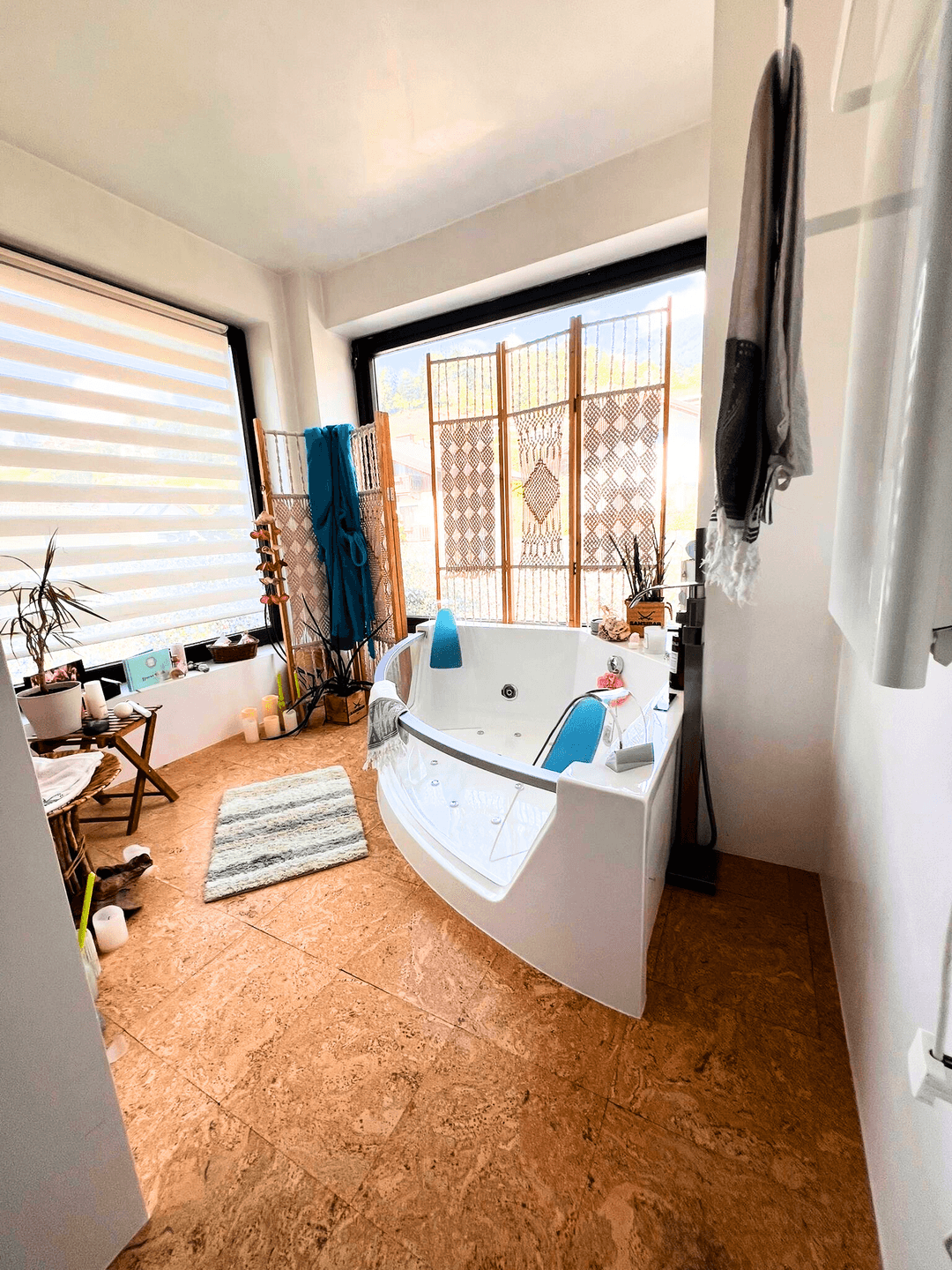 Helles Badezimmer mit Whirlpool-Badewanne, Korkboden und großem Fenster.