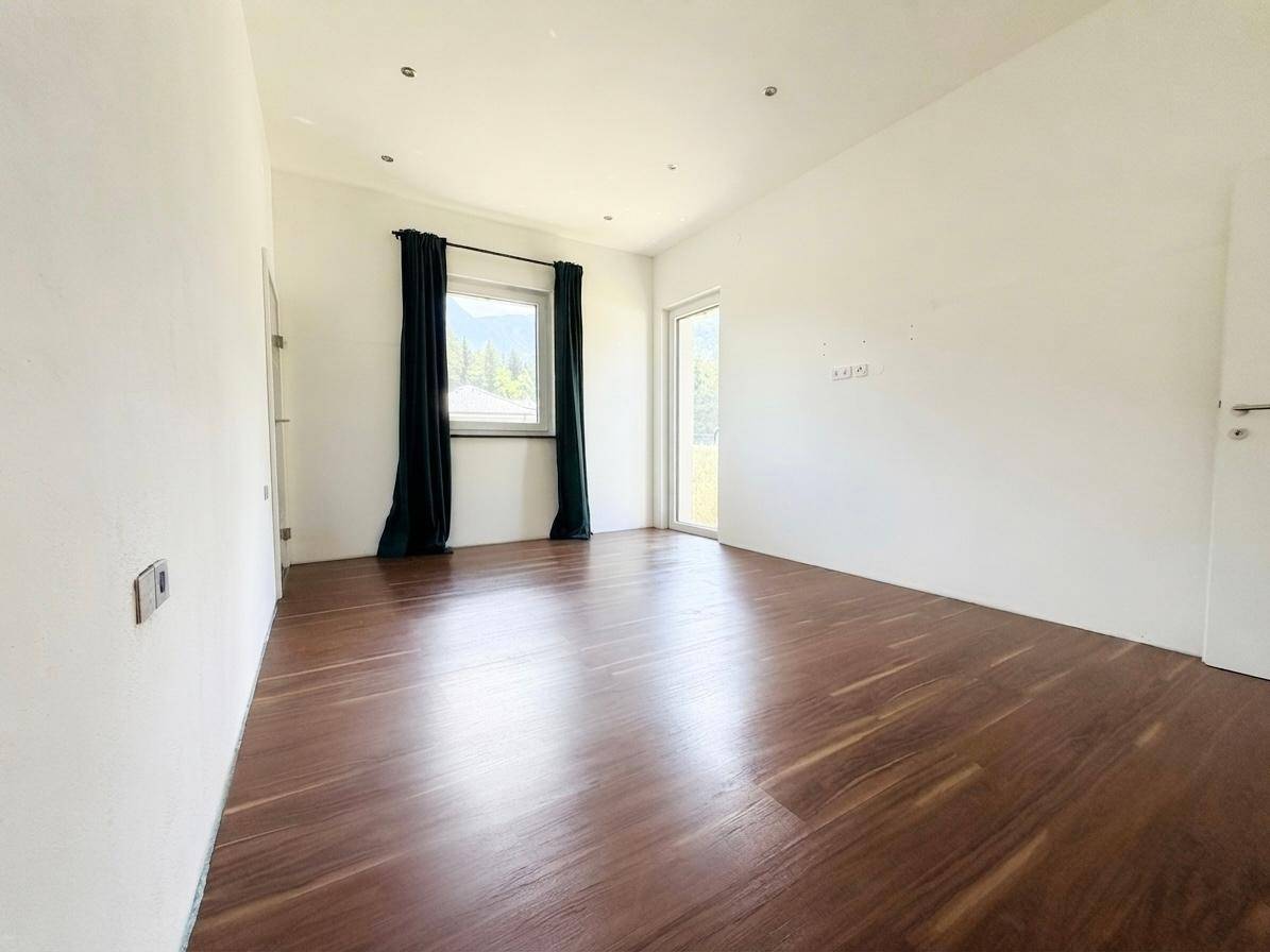 Helles Zimmer mit Laminatboden, großen Fenstern und Zugang nach draußen, mit Bergblick.