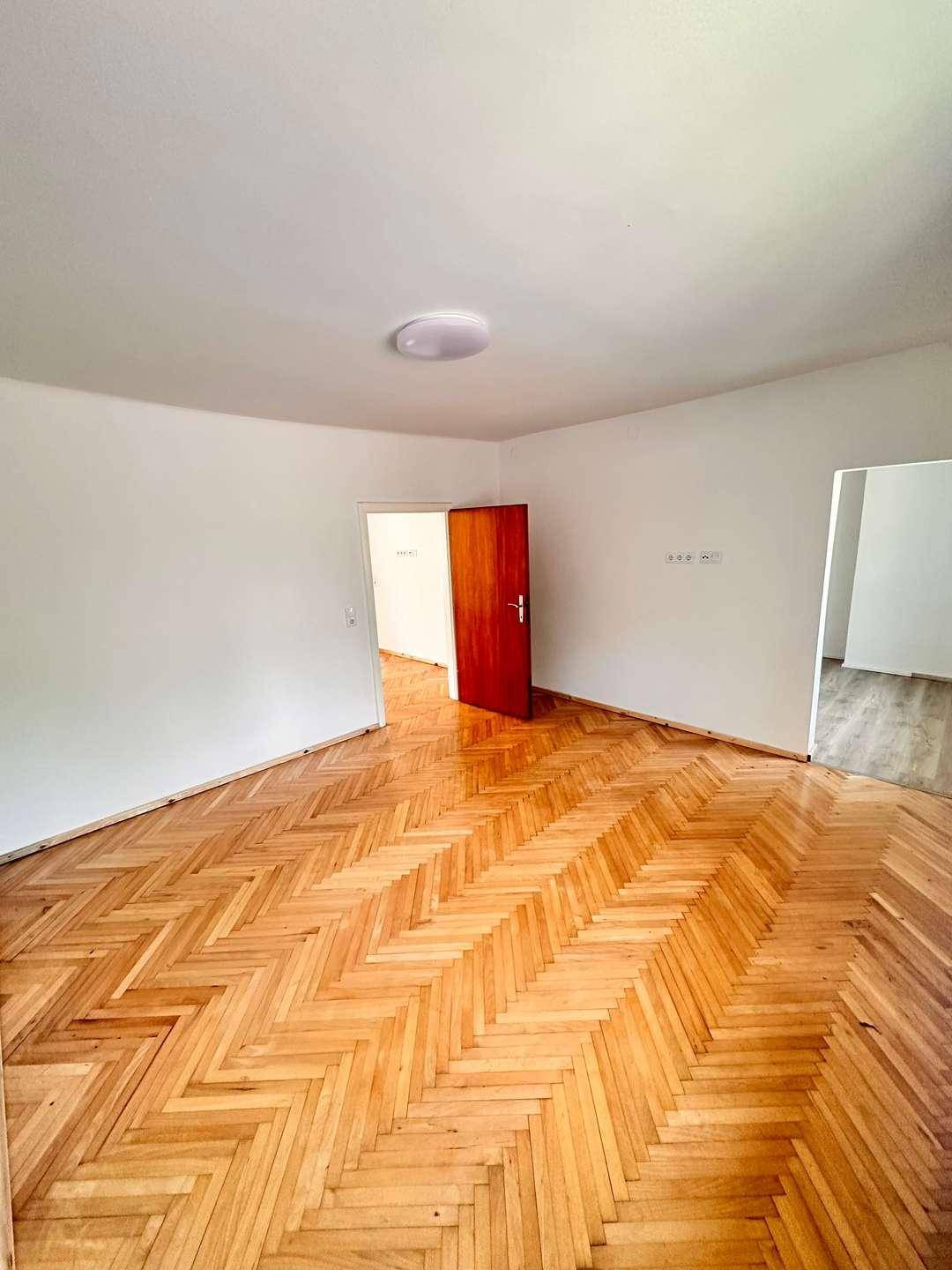 Geräumiges Zimmer mit Fischgrätparkettboden und weißen Wänden, bereit zur individuellen Gestaltung.