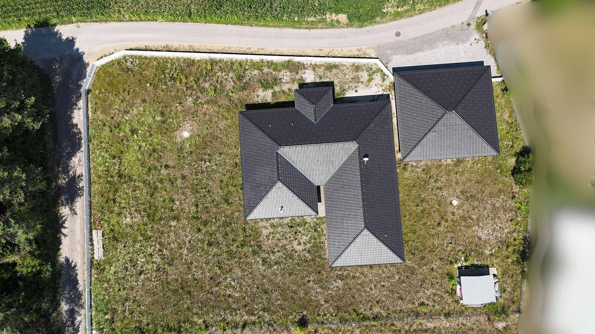 Draufsicht auf das moderne Haus und den separaten Carport mit großem Grundstück.