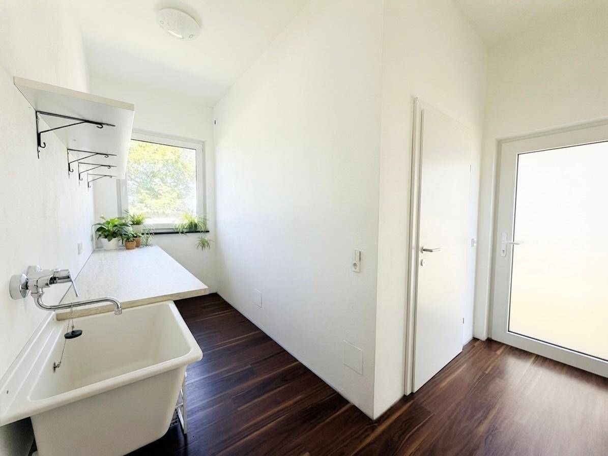 Praktischer Hauswirtschaftsraum mit Waschbecken, Arbeitsfläche und Fenster für natürliche Belüftung.