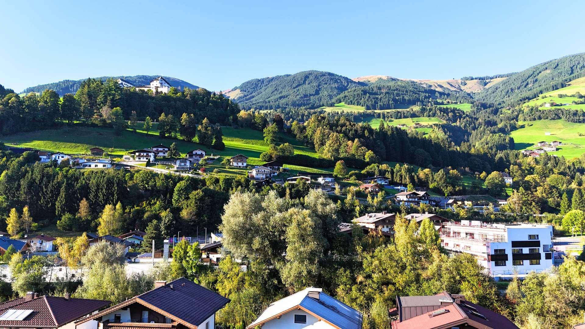 Weitläufiger Blick über eine grüne Hügellandschaft mit verstreuten Häusern.