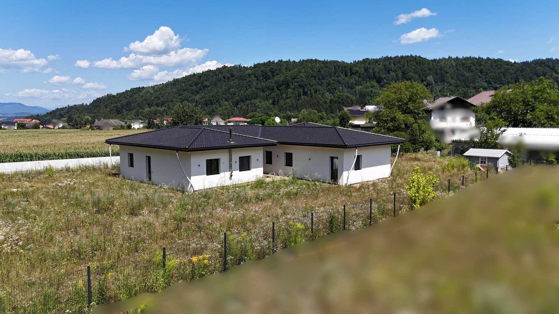 Rückansicht des Einfamilienhauses mit großem Grundstück und Blick auf bewaldete Hügel.
