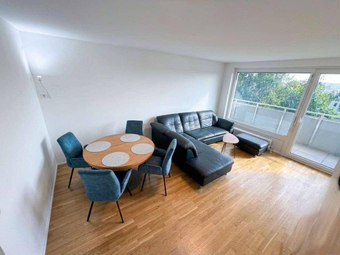 Lichtdurchfluteter Wohn- und Essbereich mit Holzboden und direktem Zugang zum Balkon.