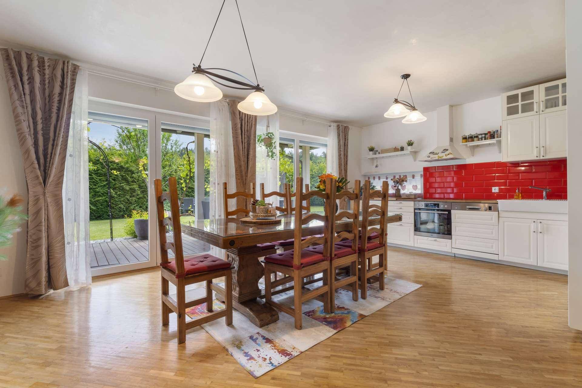 Offener Wohn-Essbereich mit Holztisch, moderner Küche und Zugang zur Terrasse.
