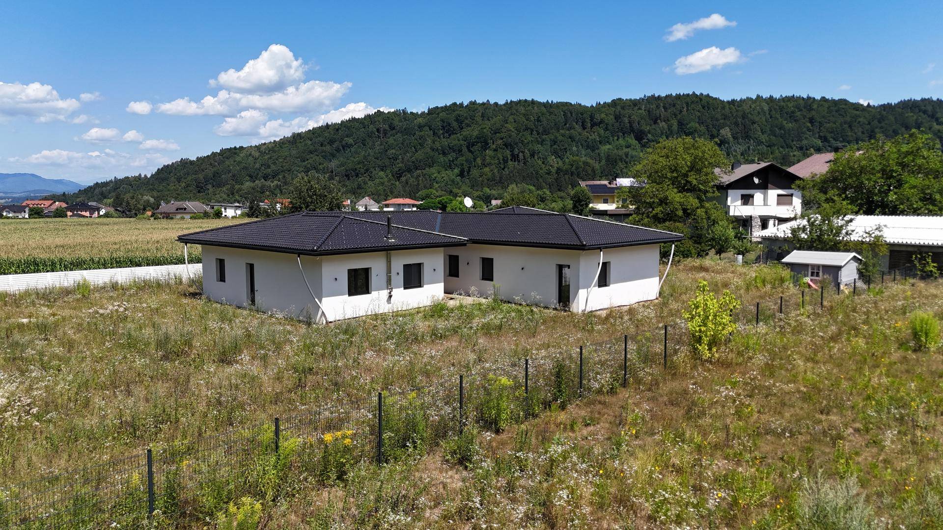 Rückansicht des modernen Hauses mit weitem Blick über Felder und bewaldete Hügel in der Ferne.