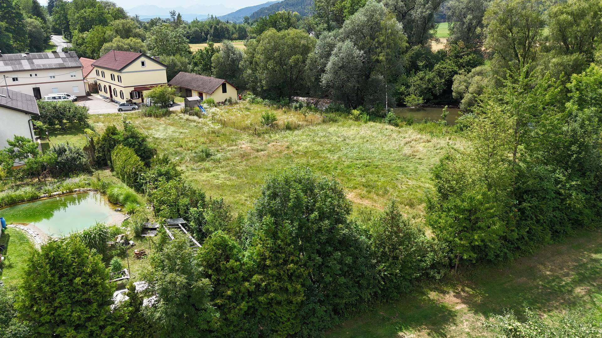 Nahaufnahme einer ländlichen Umgebung mit einem Grundstück, angrenzendem Fluss und viel Grün.