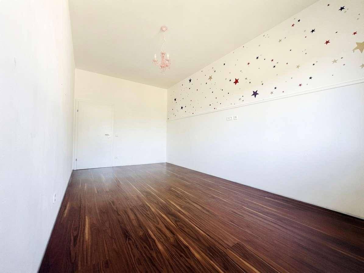 Helles Kinderzimmer mit Holzboden und Sternenmuster an der Wand, ideal für kleine Bewohner.