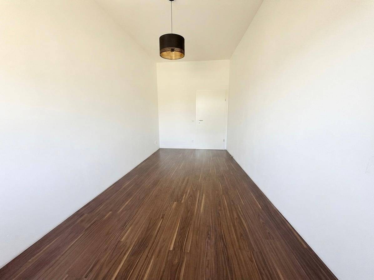 Leerer Raum mit Holzboden und schlichtem Design, bereit für individuelle Gestaltungsmöglichkeiten.