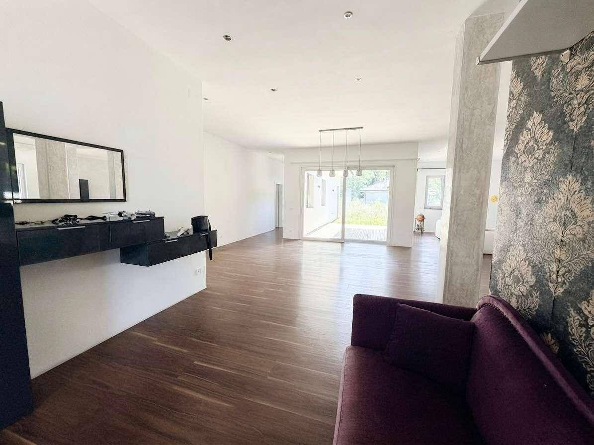 Helles Wohnzimmer mit dunklem Holzboden, moderner Einrichtung und viel natürlichem Licht.