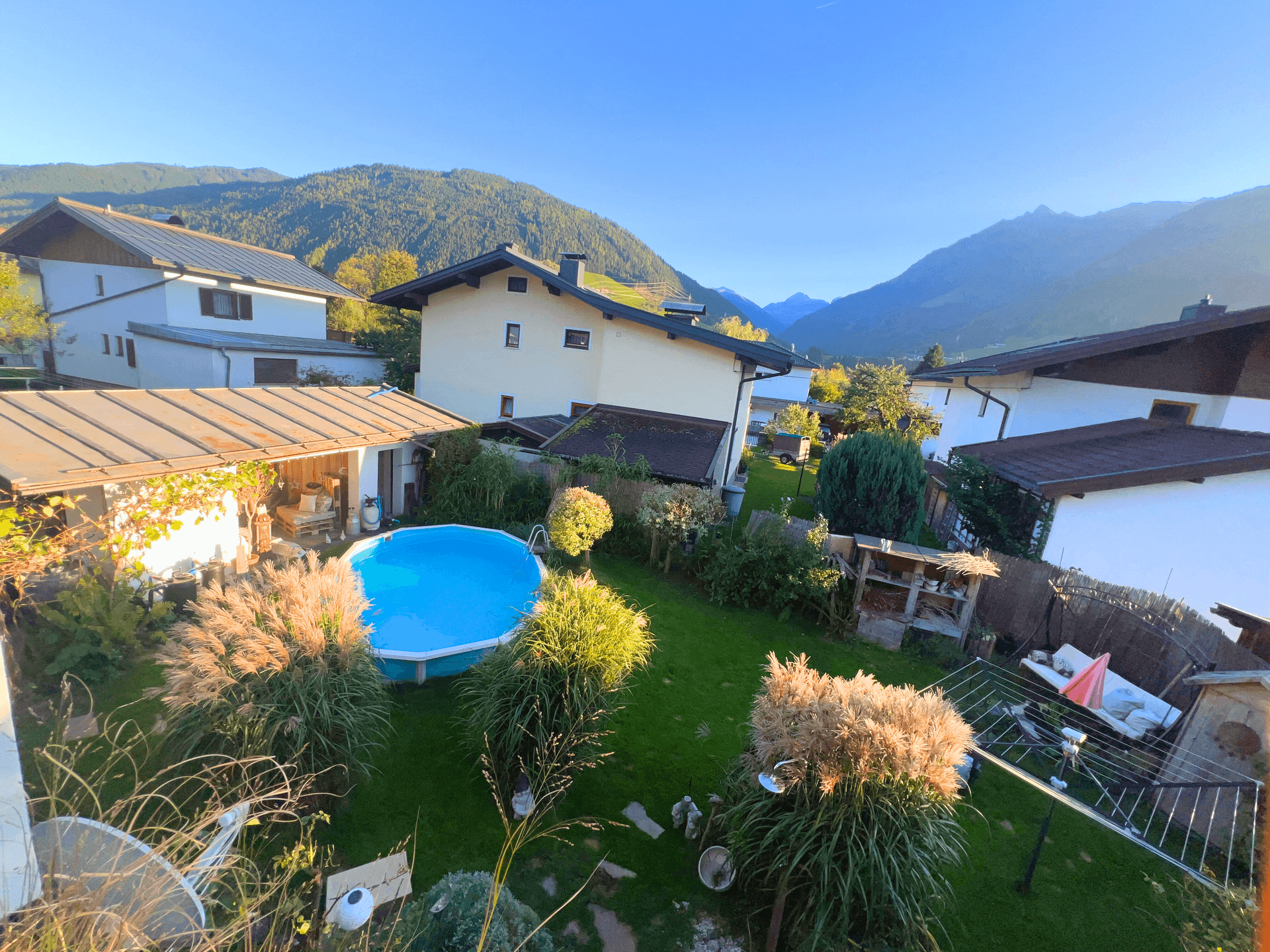 Großer Garten mit Rasenfläche, Aufstellpool und Blick auf die umliegende Berglandschaft.