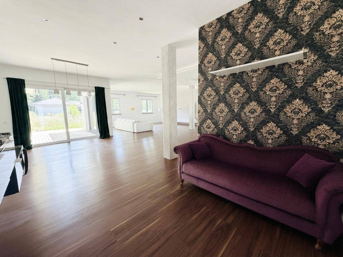 Geräumiges Wohnzimmer mit dunklem Holzboden, einer violetten Couch und auffälliger Tapete.