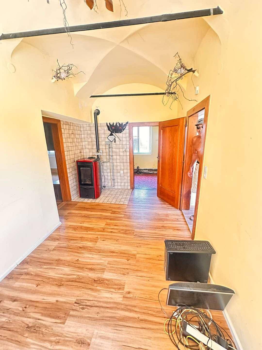Geräumiger Raum mit gewölbter Decke und einem gemütlichen Holzofen in der Ecke.