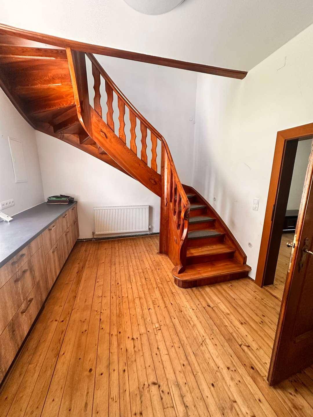 Rustikale Holztreppe mit gedrechselten Geländerstäben, die in die obere Etage führt.