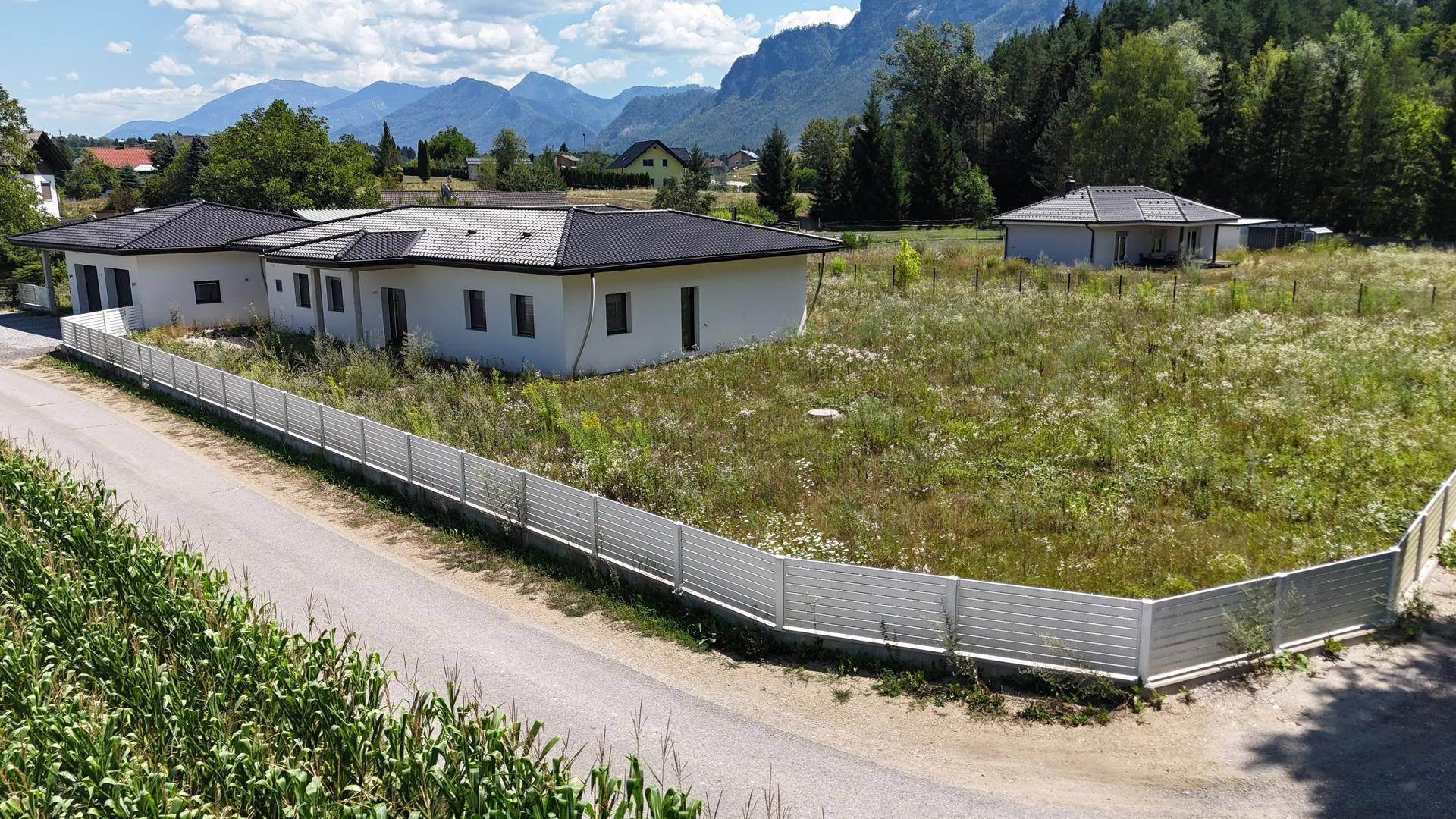 Das Anwesen mit zwei Gebäuden und weitläufigem Grundstück, umrahmt von einer malerischen Berglandschaft.