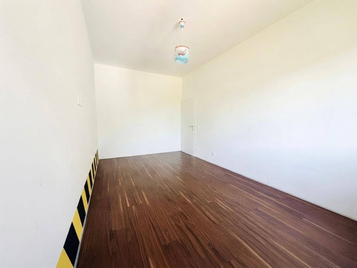 Geräumiges Zimmer mit Holzboden und kreativer gelb-schwarz gestreifter Wandgestaltung.
