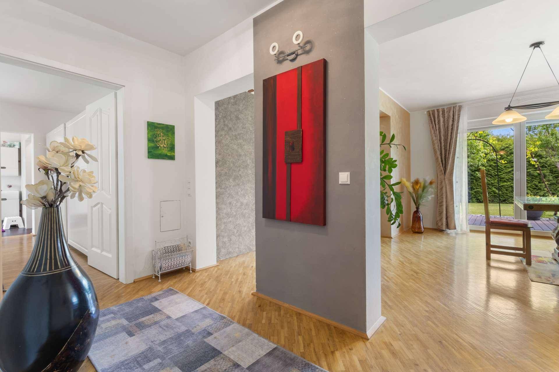 Heller Flur mit Parkettboden, moderner Kunst und Übergang zum offenen Wohnbereich.
