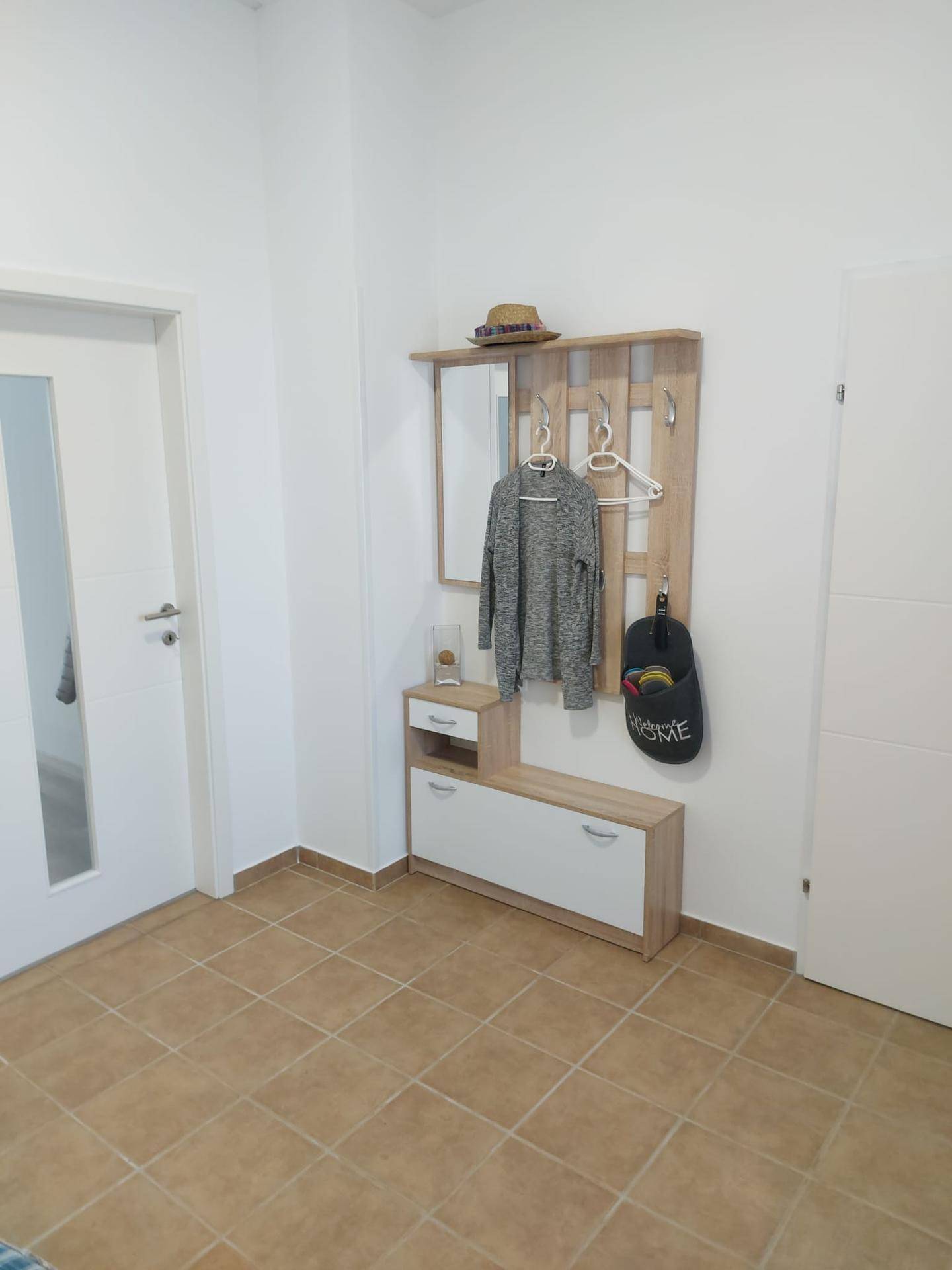 Eingangsbereich mit Garderobe, Spiegel und Schuhbank, ausgestattet mit Terrakotta-Fliesenboden.