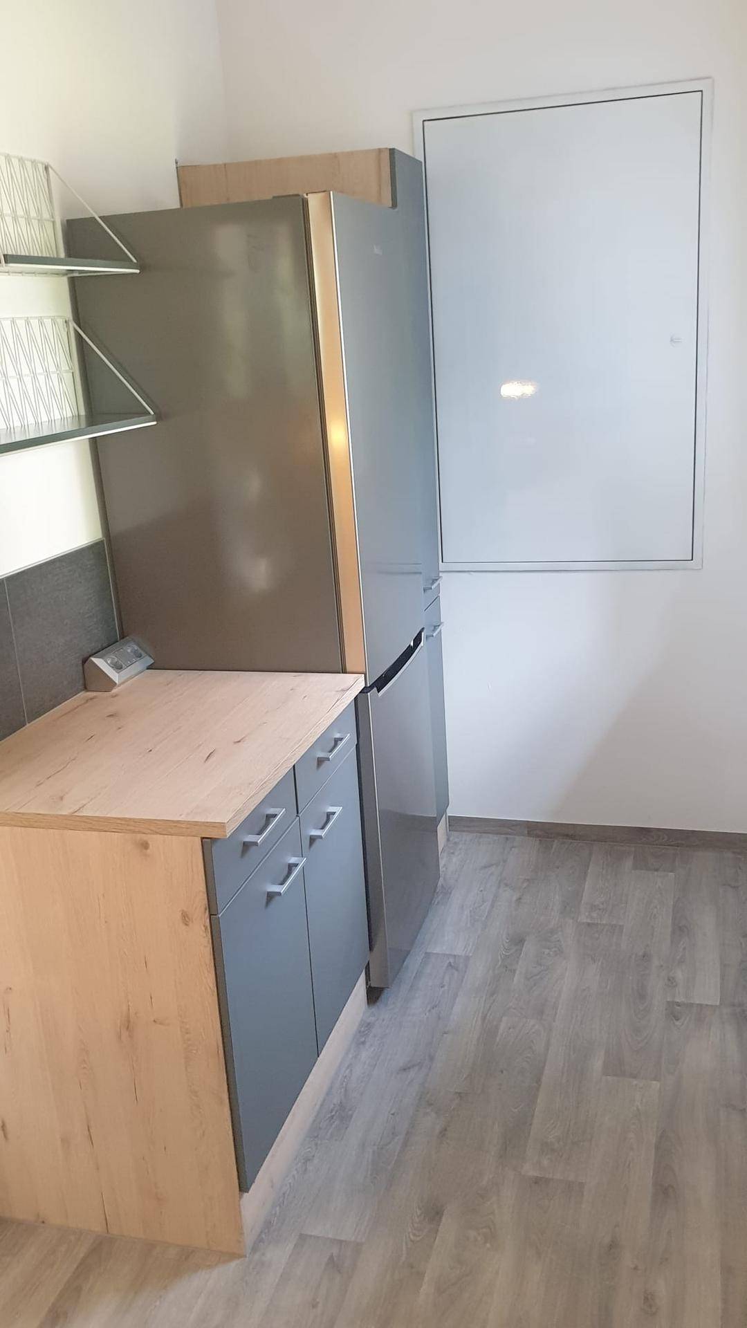 Bereich der Küchenzeile mit Platz für einen Kühlschrank und weiteren Stauraum.