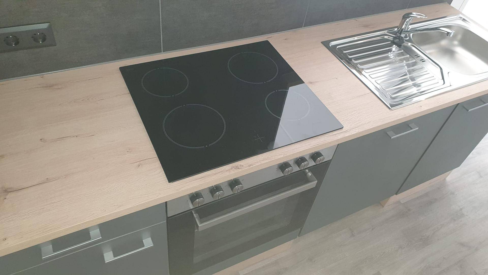 Nahaufnahme des Induktionskochfelds und Backofens in einer modernen Küchenzeile mit Holz-Arbeitsplatte.