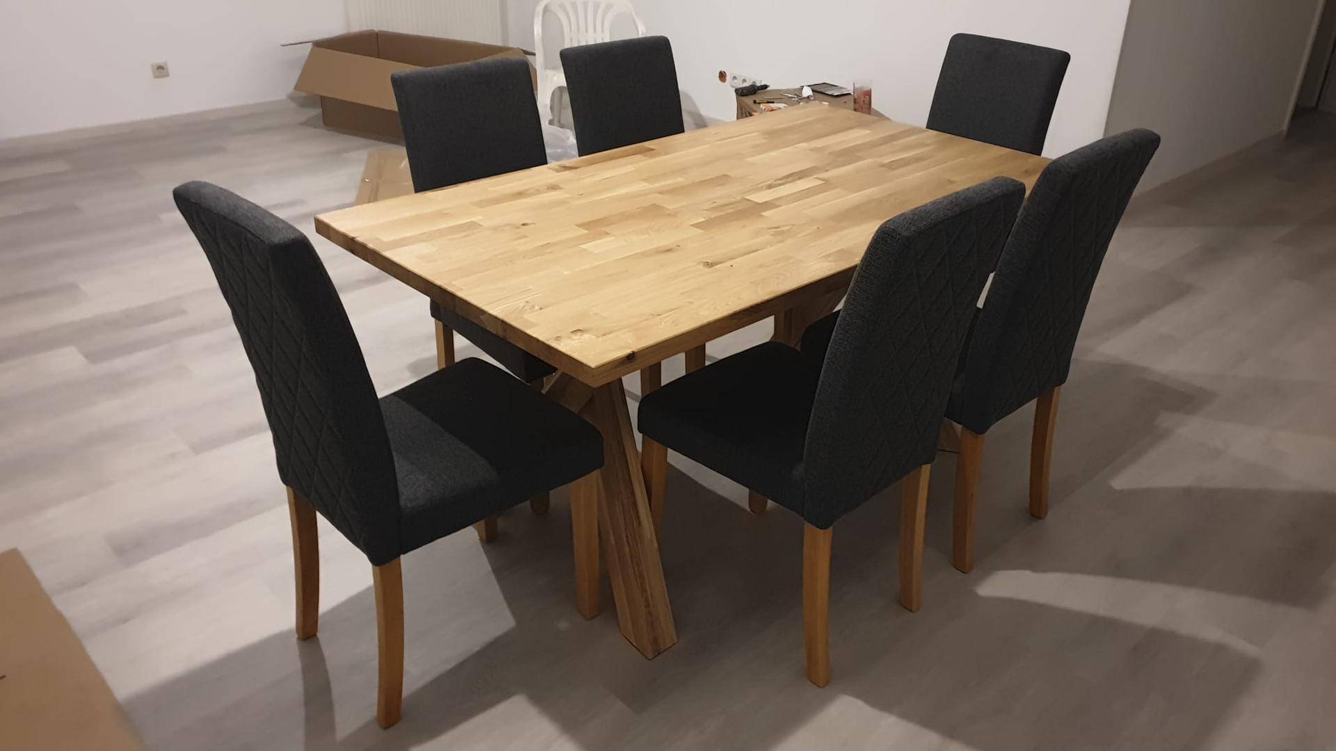 Robuster Holzesstisch mit sechs dunklen Stühlen in einem hellen Essbereich, bereit für Mahlzeiten.